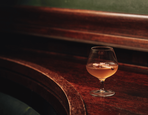 An Alpine Tales cocktail at The Delaunay Bar, elegantly presented on a dark wooden table — a showcase of the bar’s new folklore-inspired cocktail menu.
