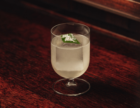 An Alpine Tales cocktail at The Delaunay Bar, elegantly presented on a dark wooden table — a showcase of the bar’s new folklore-inspired cocktail menu.